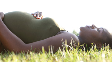 pregnant woman lying in the grass looking at the sky