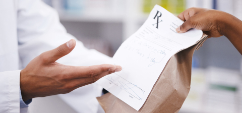 close-up of pharmacist hands giving prescription in a brown bag to patient